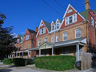 Street of large old semi-detached brick houses with front porches and gables
