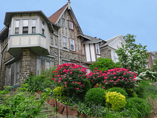 Street of large old semi-detached tudor style stones houses with gables and lush hillside front...