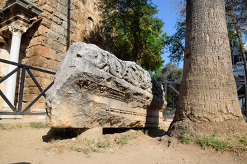 Obraz premium The element of the gate of Hadrian on the ground near the gate. Ruins of ancient construction.