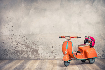 Retro orange toy aged rusty children's pedal scooter from 60s and red helmet with aviator goggles...