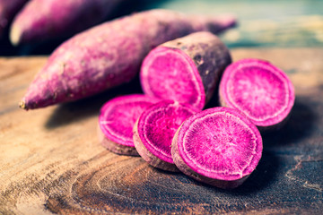 Obraz na płótnie Canvas Purple sweet potatoes on wooden background