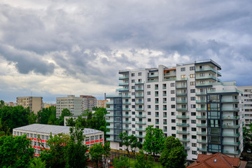 White, empty apartments building with stormy clouds above. Generic modern architecture in East...