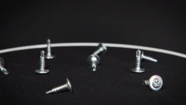 Screws spinning on a black background. Self-tapping screws on a black background.