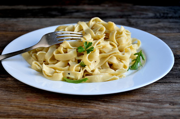 Homemade noodles in a ceramic plate with greens.