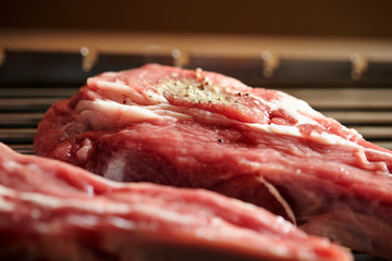 Fresh raw meat with seasoning on grill