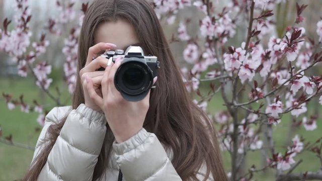 Happy photographer on nature. Beautiful girl photographer taking pictures of sakura blossom.