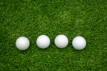 Four golf balls are on green grass background