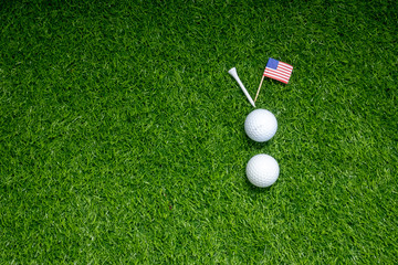 Golf ball with flag of America on green grass.
