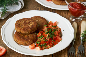 Buckwheat cutlets with fresh tomato salad on a white plate