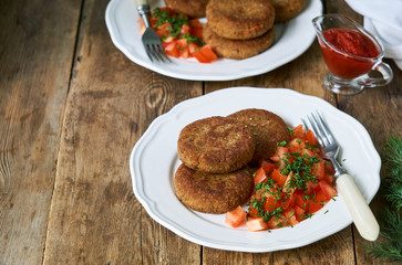 Buckwheat cutlets with fresh tomato salad on a white plate