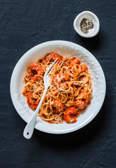 Shrimp tomato sauce spaghetti on a dark background, top view