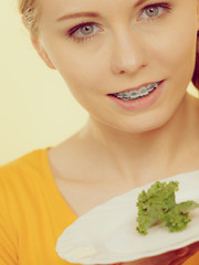 Smiling woman holding plate with lettuce