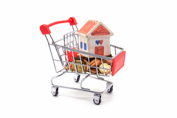 House model in mini shopping cart with stack of coins money on white blackground