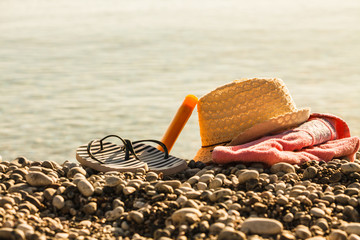 Sun hat and flip flops on stone beach