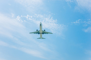 Fototapeta na wymiar airplane flying over head against blue sky and clouds