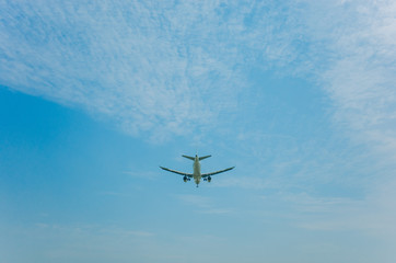 airplane flying over head against blue sky and clouds