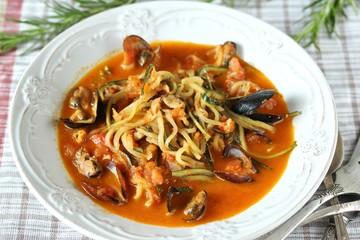 zucchini spaghetti with mussels in tomato sauce in a beautiful bright plate. keto pasta. Low-Carb