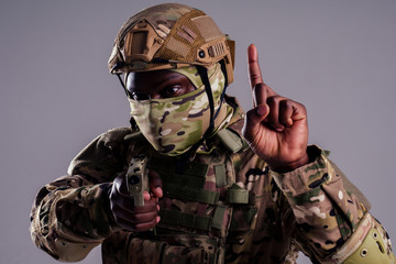 american man in camouflage suit aiming with a pistol studio shot