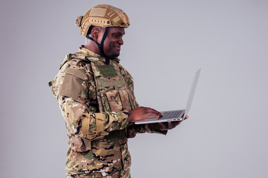African American soldier smiles while typing a computer videocall with wife and child