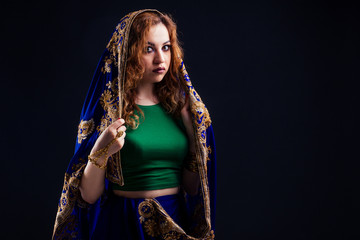 indian beautiful fashion brunette woman in green traditional wedding rich sari with gold jewelry set nose ring piercing nath professional make-up on black studio background eastern belly dance