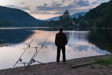 Fishing adventures, carp fishing at sunset. Man on lake