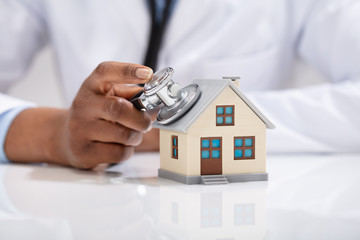 Doctor Using Stethoscope To Check Model House