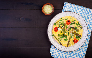 Omelette with asparagus and tomato for breakfast on a wooden background. Top view