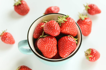ripe strawberries in a blue cup on a white background