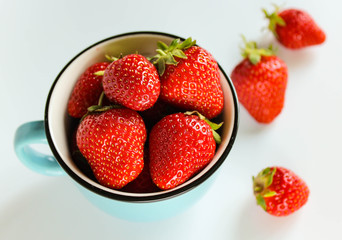 ripe strawberries in a blue cup on a white background