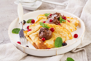 Pancakes with berries and chocolate decorated with mint leaf. Tasty breakfast.