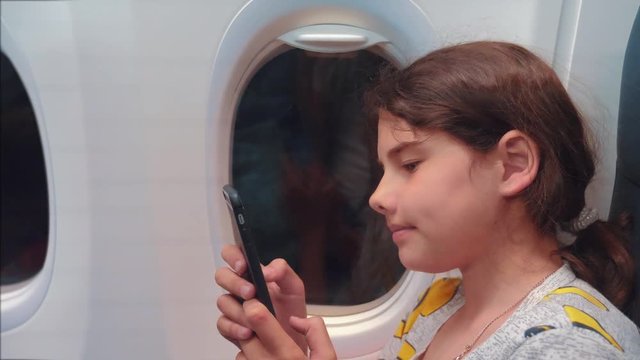aviation aircraft concept. young girl is flying on a plane inside next to the window is chatting looking in the smartphone in the messenger flight lifestyle at night by airplane