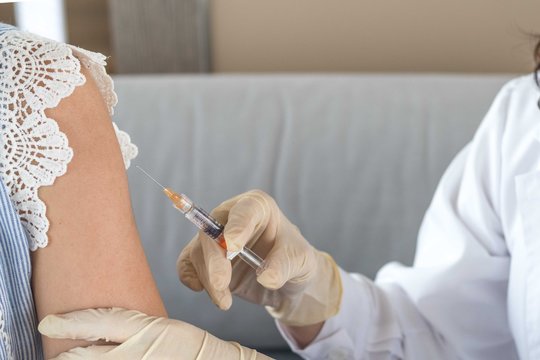 World immunization week and International HPV awareness day concept. Woman having vaccination for influenza or flu shot or HPV prevention with syringe by nurse or medical officer.