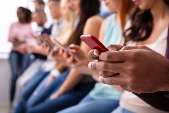 Row Of Young People Using Cellphones