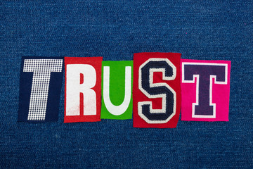 TRUST text word collage in colorful fabric on blue denim, confidence and fidelity, horizontal aspect