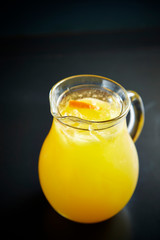 Orange juice in pitcher on black background
