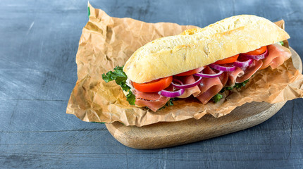 sandwich from a cereal baguette , ham, lettuce, kale on a gray background. takeaway sandwich,