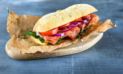 sandwich from a cereal baguette , ham, lettuce, kale on a gray background. takeaway sandwich,