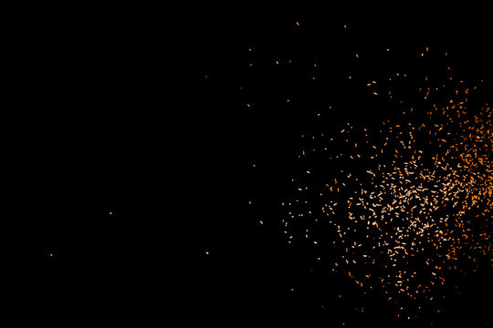 Random flying red orange color particles isolated on the black background, for overlay abstract design.