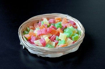Candied fruits in a wicker basket on a black background