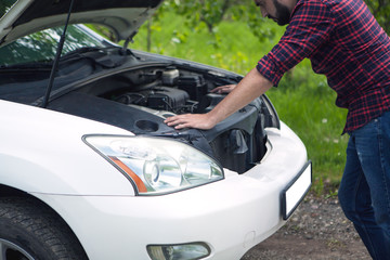 Tired man trying to fix a broken car