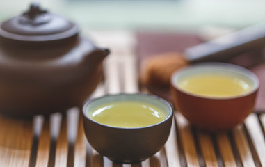 Blurred background: Gongfu ceremony with Oolong tea, teapot and two cups on a chaban