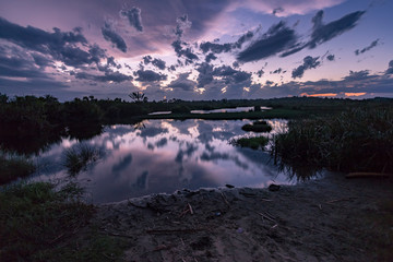Canal des Pangalanes,  Manakara, Madagascar.  Waterfront view with beautiful cloud formations after sunset and reflection on the water with tropical vegetation. 