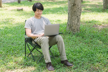 man sitting on camping chair and working with laptop computer in the garden