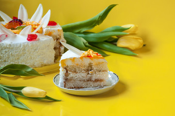 Cake and saucer with a piece of cake with a tulip flower on a yellow background