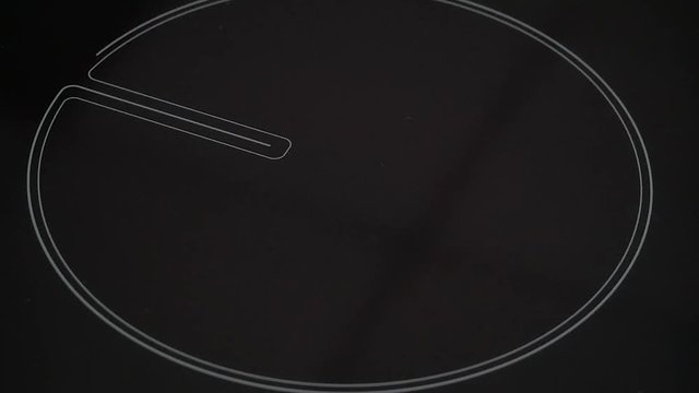 Man hand tunes (regulates) modern electric hob burner glowing bright red with heat then switches off electric cooktop.