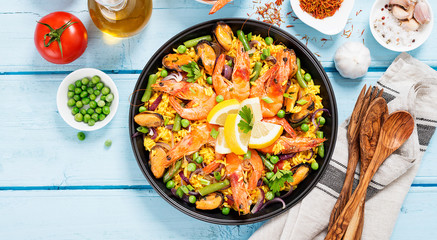 Traditional spanish seafood paella in the fry pan on a blue wooden  table, top view.