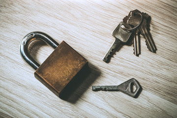 Metal lock and different keys on wooden background concept