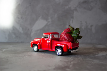 Obraz na płótnie Canvas Red strawberry on old vintage red toy truck car. Fruits and transportation concept in macro. Close-up food logistics visualisation.