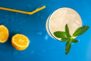 Peppermint leaves in lemonade glass on blue table