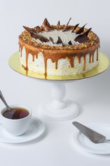 Cake with chocolate pieces and caramel and a mug of tea on a white background
